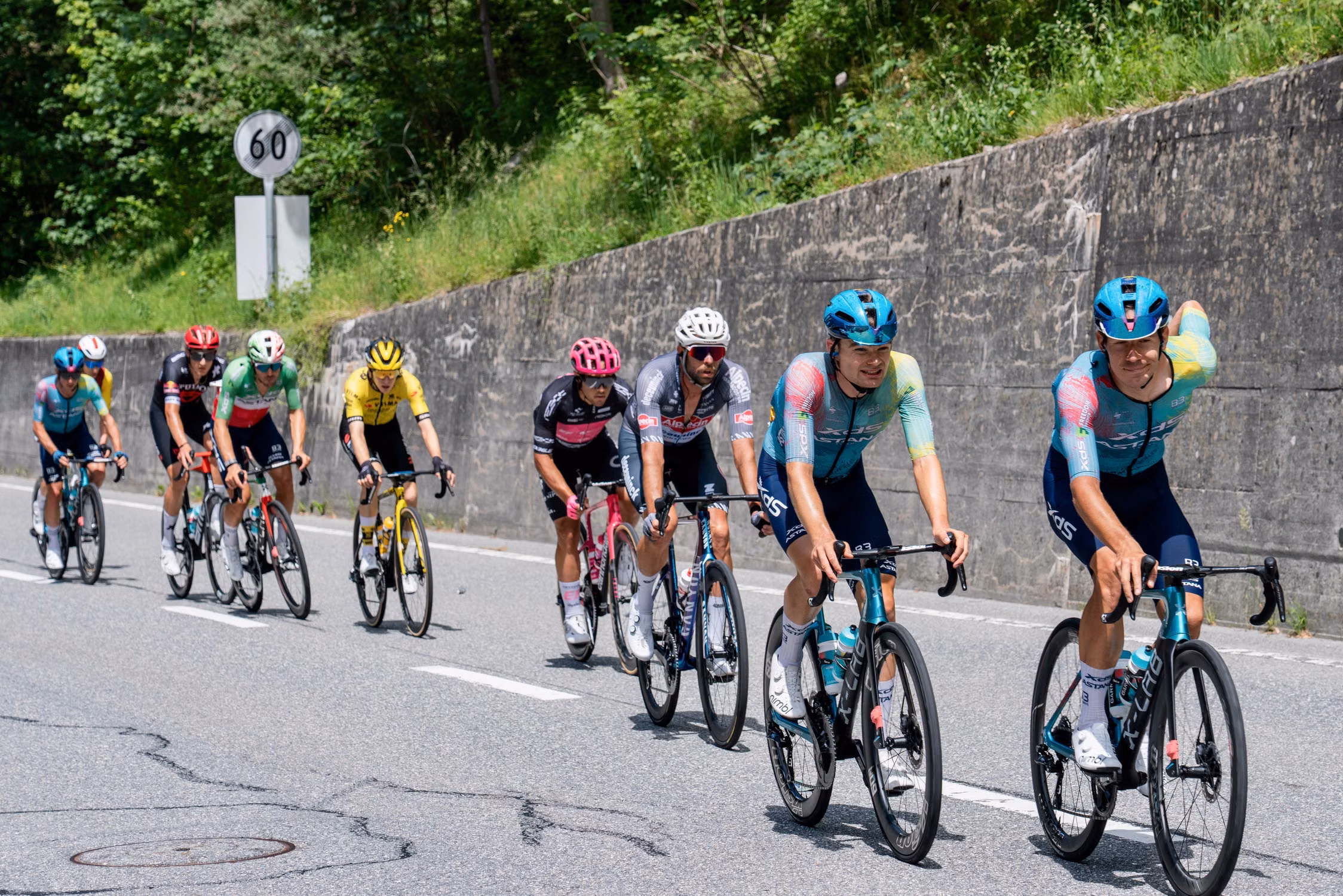 A group of cyclists riding along a mountain road.